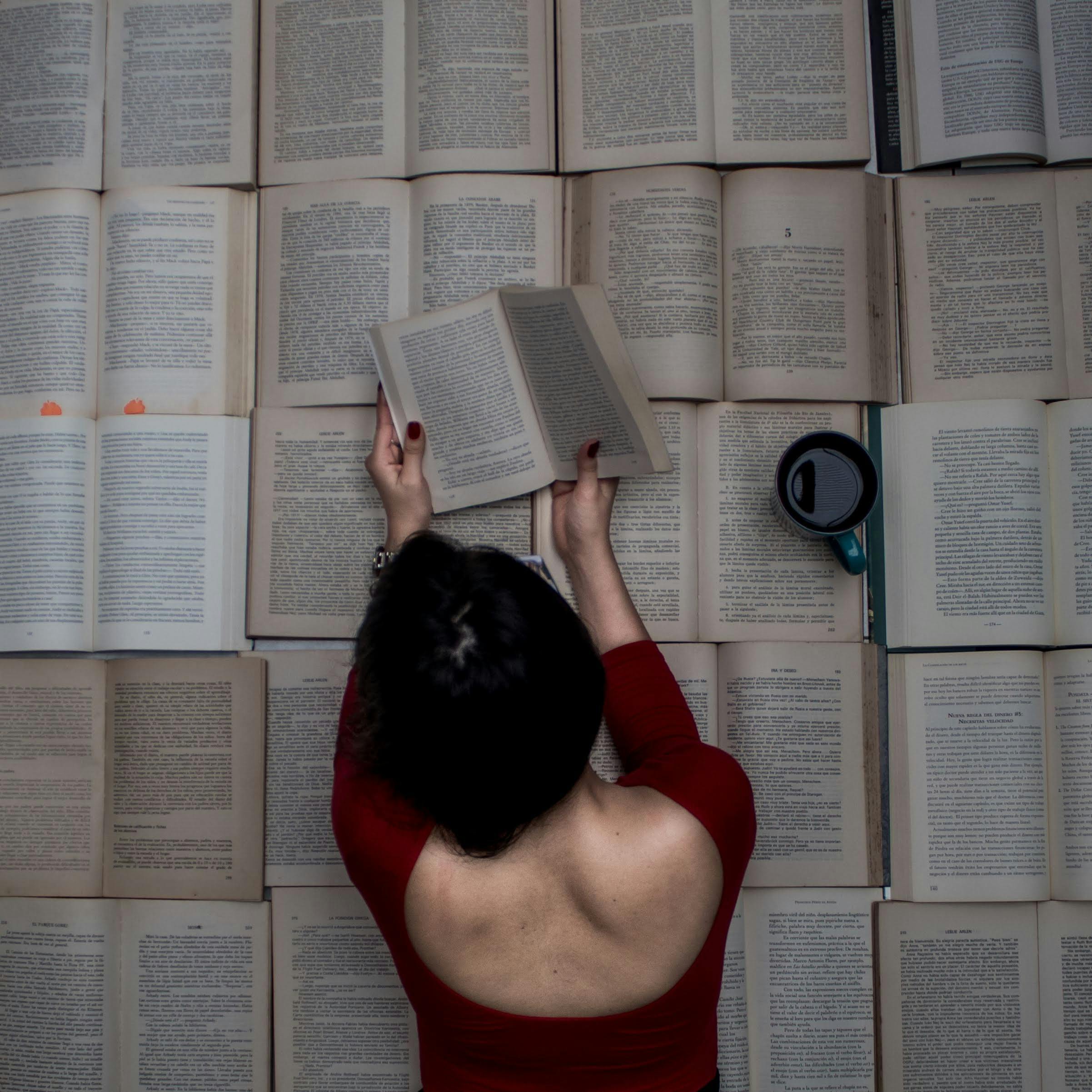 woman reads a book lying on books