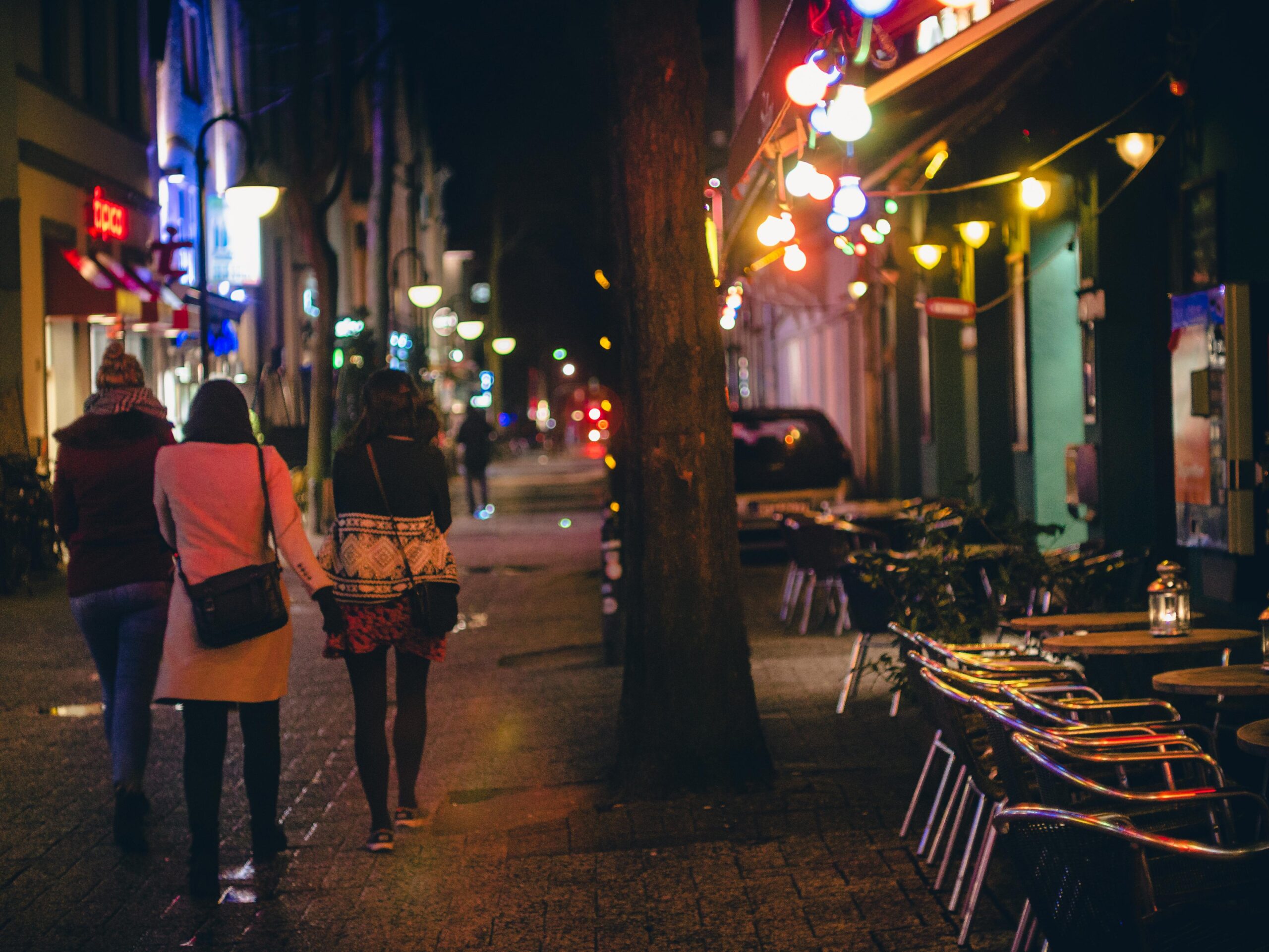 Three women walking on the street at night